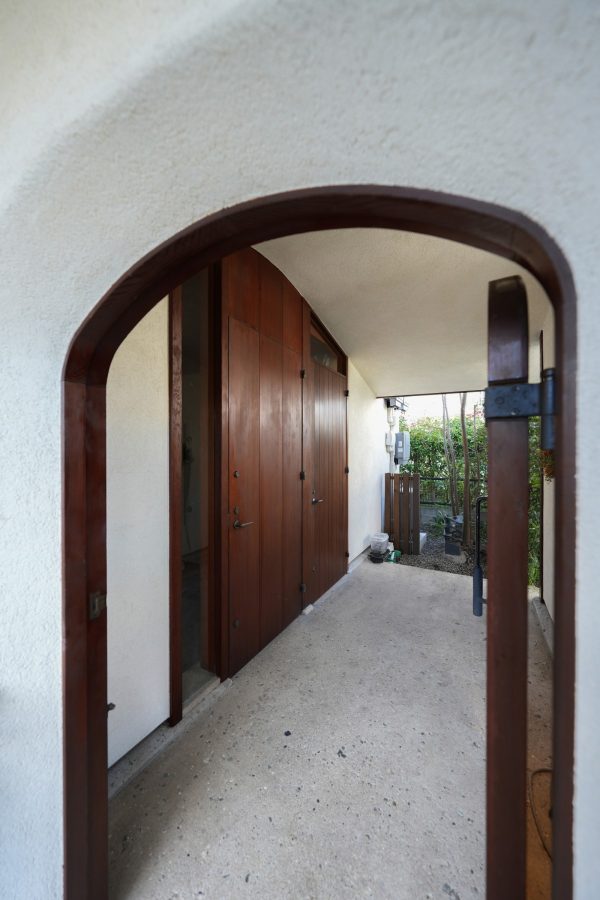 旗竿地のアプローチの先、少し低いアーチドアをくぐ ると2つの玄関が。元々は1つだった玄関を二つに分け （奥を新設）、それぞれの暮らしに配慮したつくりに。